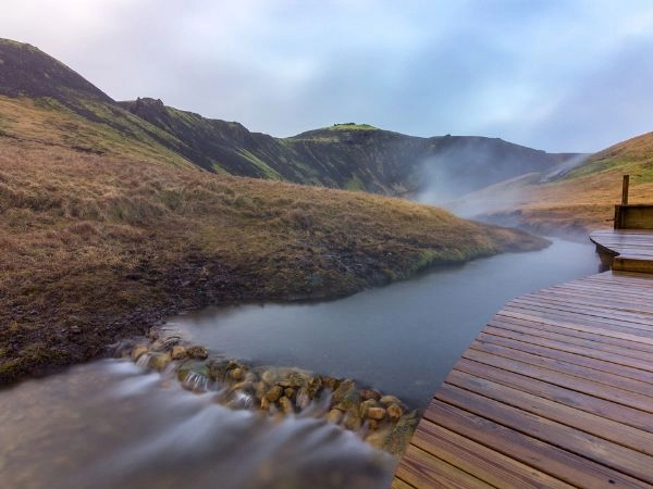 Immergersi nel fiume termale di Reykjadalur tra colline vulcaniche e vapori naturali in Islanda