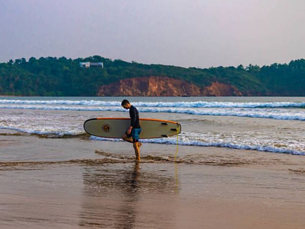 Surfista con una tavola da surf sulla spiaggia di Weligama