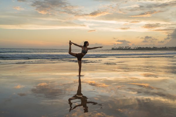 giovane-donna-prativa-yoga-sulla-spiaggia-al-tramonto